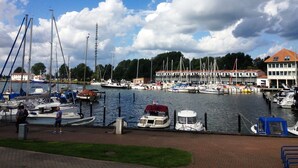 A marina with various boats docked, a building with a red roof, and a grassy area in the foreground. - Moderne Wohnung in Karlshagen mit Grill und Garten by Interhome (Karlshagen)