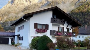 A white building with the name "Haus Rosenwirth" and a balcony with flowers. - Haus Rosenwirth by Interhome (Mittenwald)