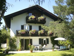 Un immeuble de deux étages doté d’un balcon orné de jardinières fleuries.