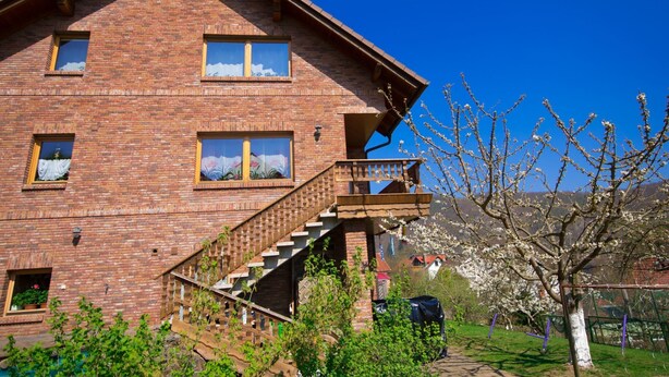 Une maison à deux étages, construite en briques, avec un escalier en bois menant à un balcon.