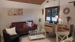 Ein gemütliches Wohnzimmer mit einem braunen Sofa, einem weißen Couchtisch und einer weißen Kommode mit Dekorationen.