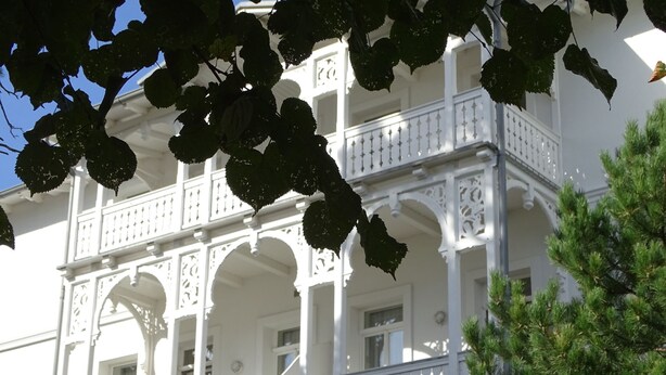 Um edifício branco com varandas elaboradas e janelas em arco.