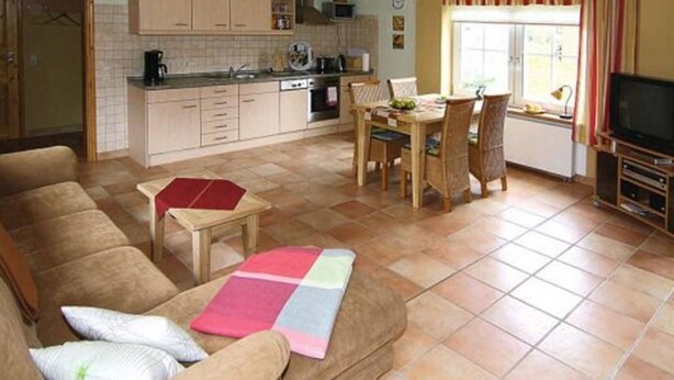Un espacio habitable compacto con kitchenette, zona de comedor y sala de estar con sofá y mesa de centro.
