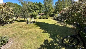 Un espacio al aire libre con césped, dos sillas y una bicicleta.