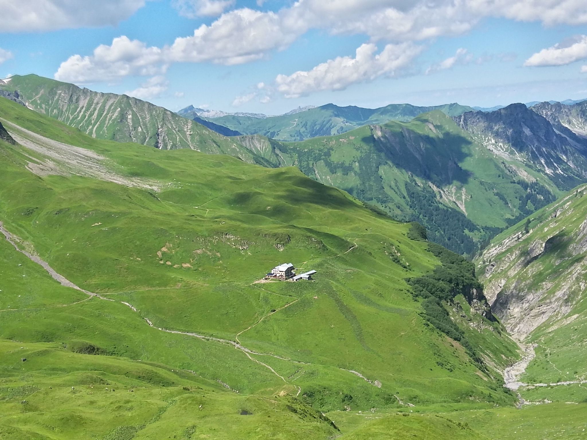 A mountainous landscape with a small building in the valley.