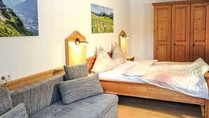 Een slaapkamer met een houten bed, een grijze bank en twee wandlampen.