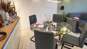 Un'area pranzo moderna con un tavolo in vetro, sedie nere e un bancone in legno con oggetti decorativi.