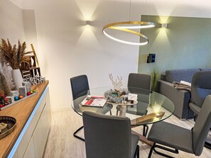 Ein moderner Essbereich mit einem Glastisch, schwarzen Stühlen und einer Holztresen mit Dekoration.