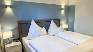 Una camera d'albergo con un letto, lampade da comodino, una sveglia digitale e un comodino.