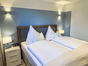 Ein Hotelzimmer mit einem Bett, Nachttischlampen, einer digitalen Uhr und einem Nachttisch.