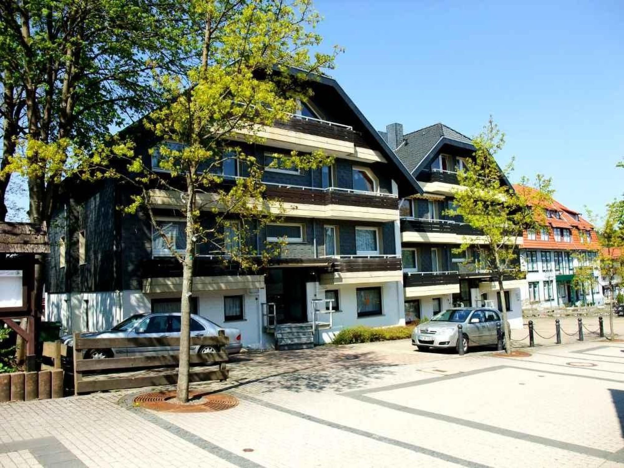 A multi-story building with balconies, a paved driveway, and parked cars.