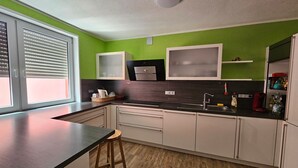 Eine moderne Küche mit schwarzem Arbeitsplatz, weißen Schränken und einer grünen Akzentwand.