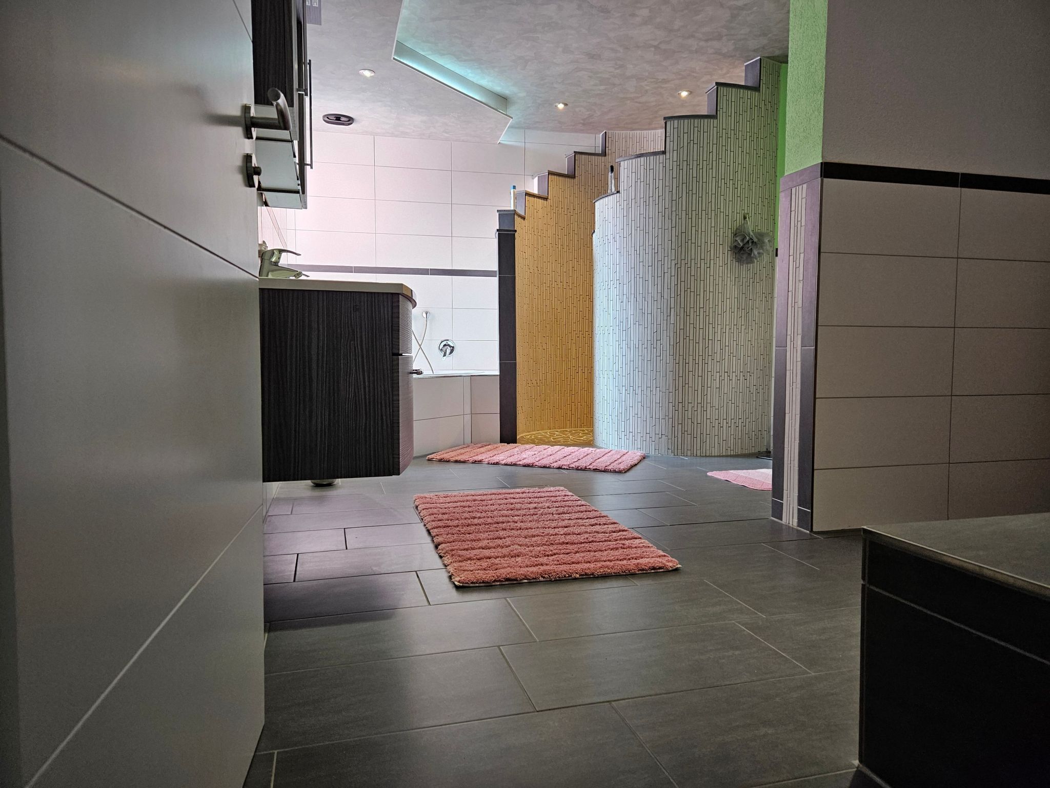Ein moderner Flur mit einem dunklen Holzschrank, einem rosa Teppich und einer Treppe mit Holzwangen.