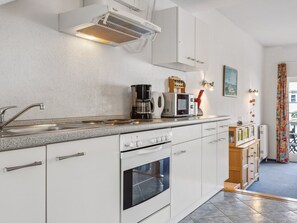 Eine moderne Küche mit weißen Schränken, einem Backofen, einer Kaffeemaschine und einer Mikrowelle.
