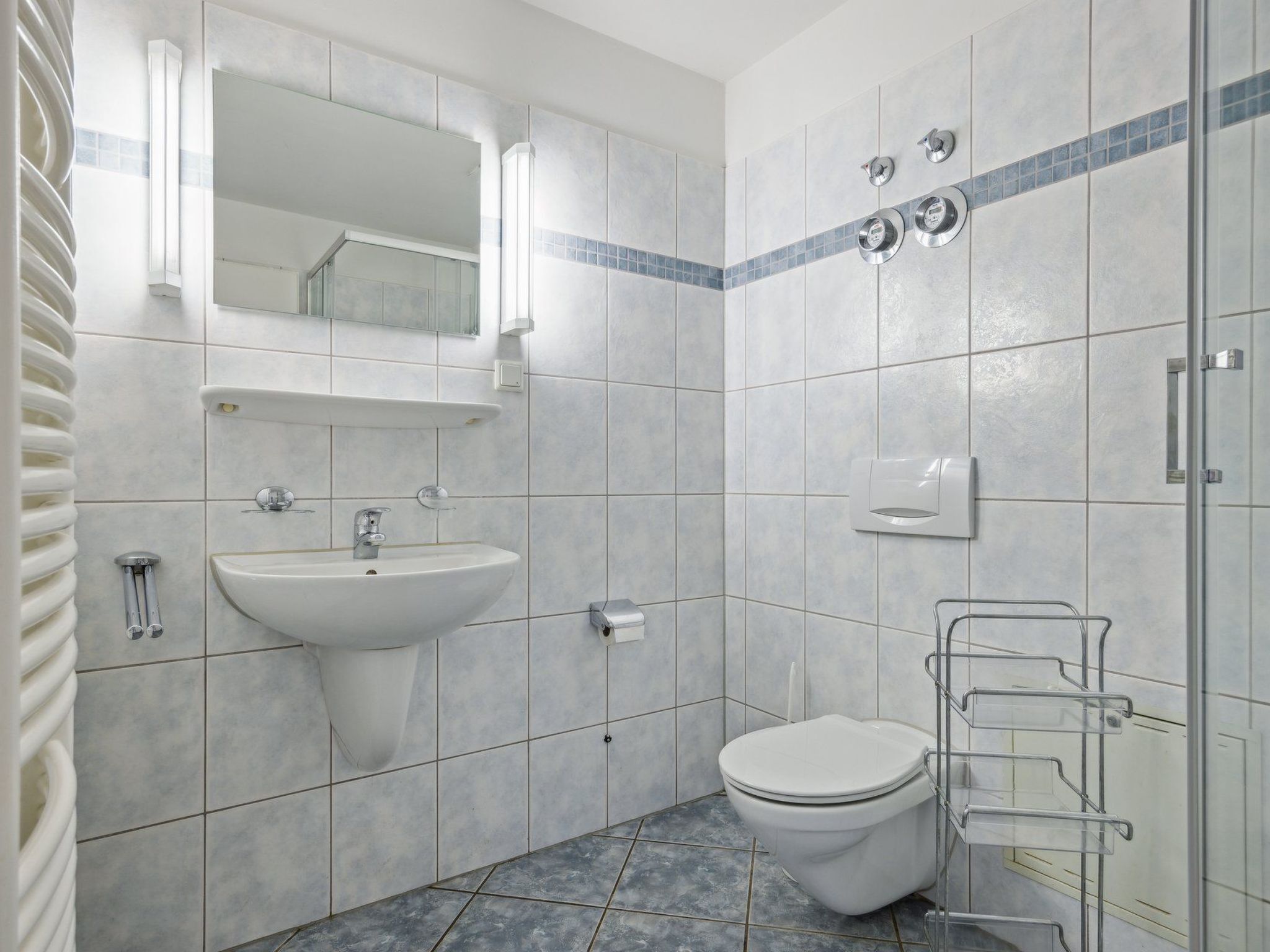 A modern bathroom with a white sink, mirror, and toilet.
