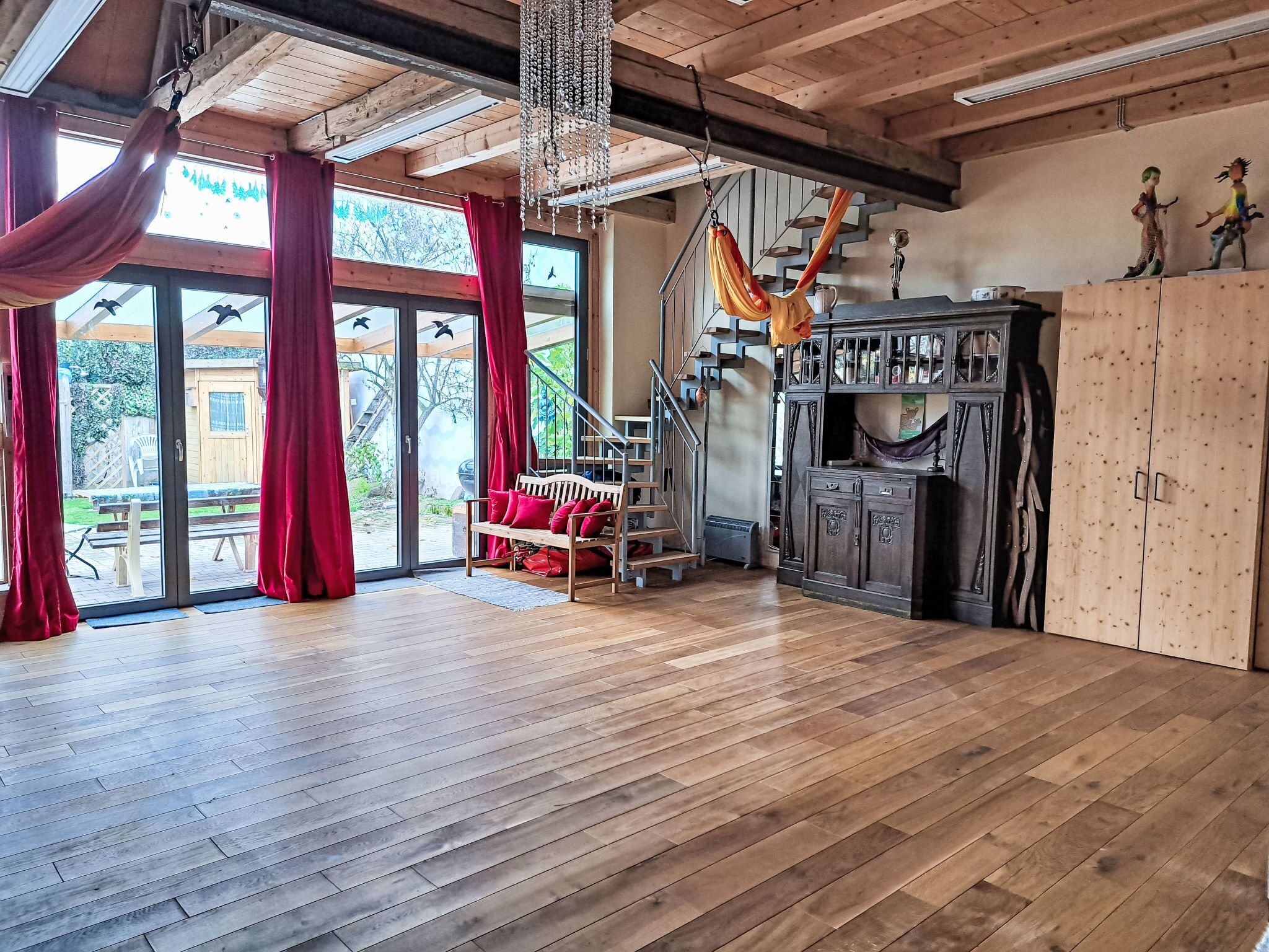 Una habitación amplia con piso de madera, una hamaca, una escalera y un armario grande.