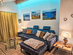 A modern living room with a blue sofa, a glass coffee table, and a wooden side table with a lamp. - Tegernsee Stern bei Rottach-Egern by Interhome (Rottach-Egern)