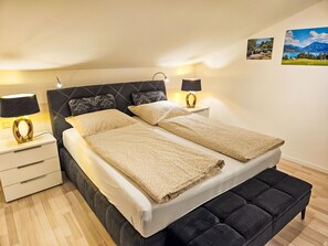 A bedroom with a bed, two bedside tables, a bench, and wall art. - Tegernsee Stern bei Rottach-Egern by Interhome (Rottach-Egern)