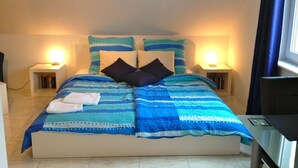 Un letto rifatto con cura, con una coperta a righe blu e bianche e due cuscini, affiancato da comodini con lampade.