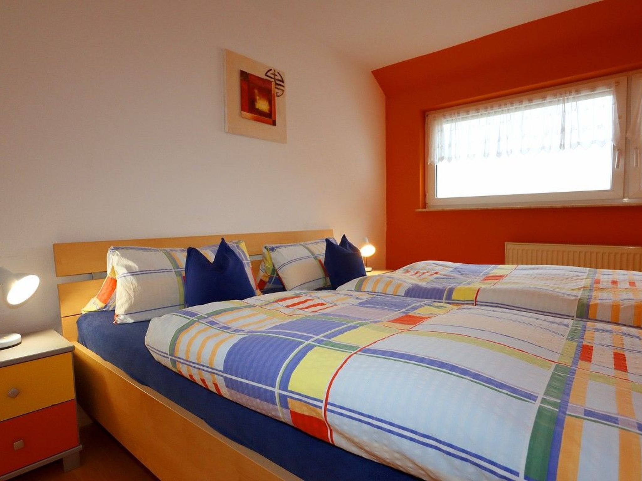 A bedroom with a bed, bedside tables, and a window.