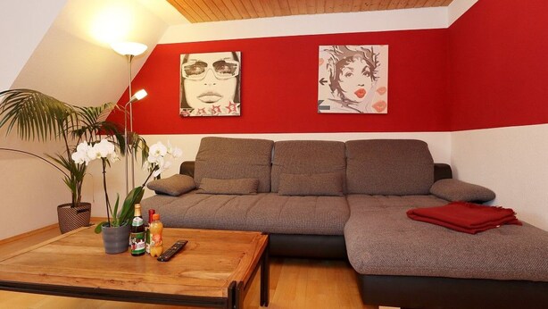 Un soggiorno moderno con soffitto in legno, un divano grigio e pareti rosse.