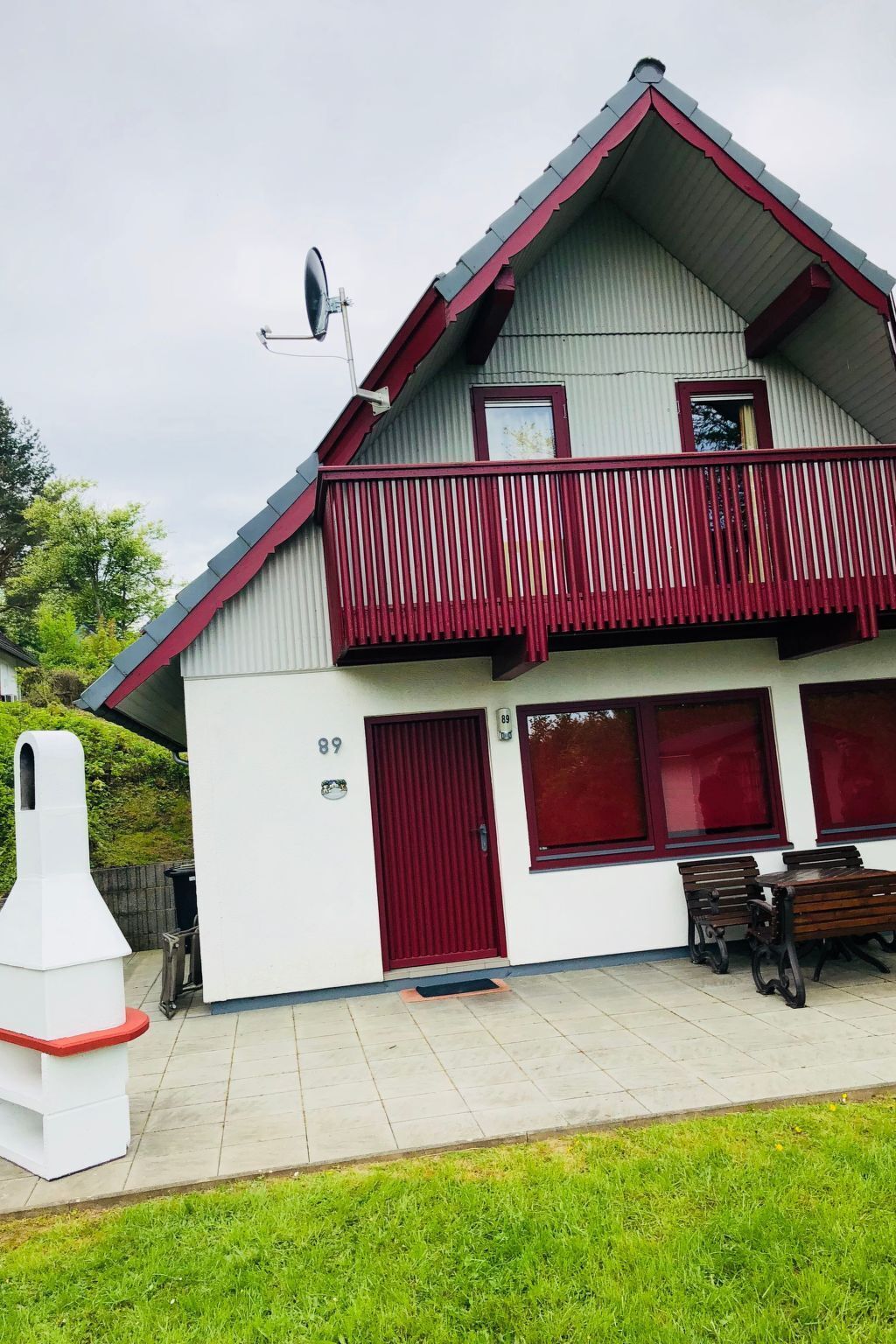 Ein zweigeschossiges Gebäude mit einem roten Balkon, einer Satellitenschüssel und einem Schild mit der Nummer 89.