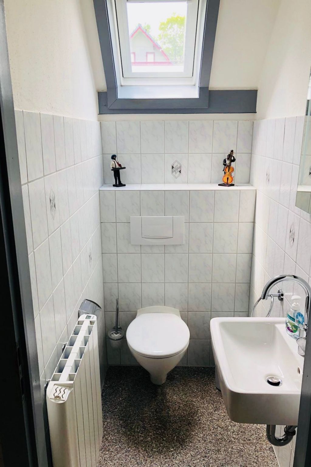 A small bathroom with a toilet, sink, and a skylight above the toilet.