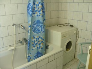Une salle de bain avec une baignoire, un lave-linge et une douche.