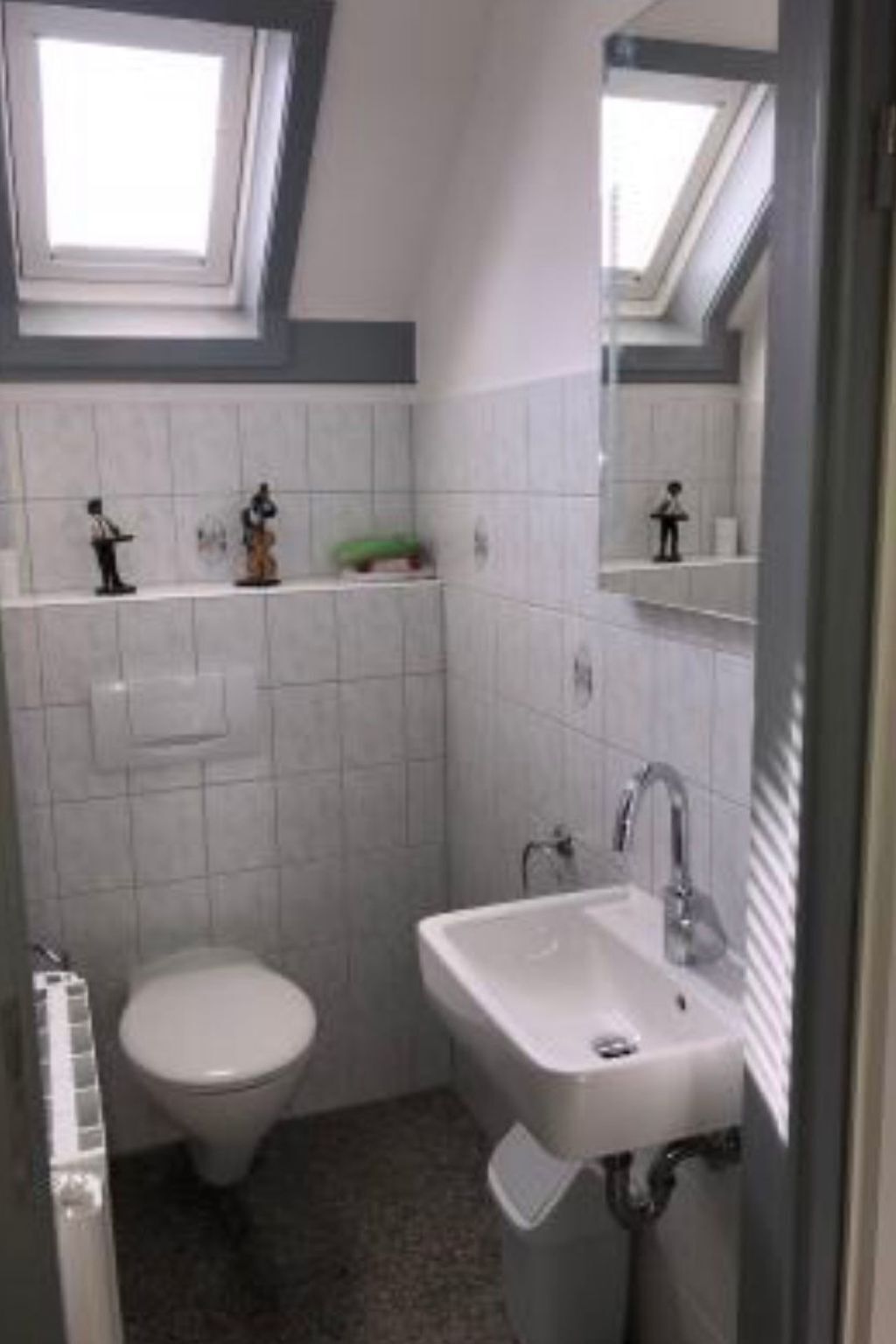 A small bathroom with a toilet, sink, and a skylight.