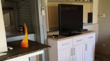 Een compact woongedeelte met een kitchenette, een flatscreen televisie en een eethoek.