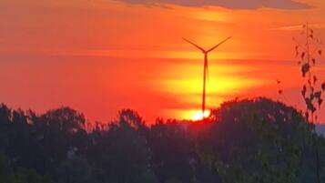 Ein Sonnenuntergang mit einer gegen den Himmel abgesetzten Windkraftanlage.
