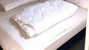 A single bed with white bedding in a room with wooden panel walls and a sloped ceiling. - Stausee in Kirchheim Seepark by Interhome (Kirchheim)