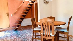 Un comedor con una mesa y sillas de madera, suelo estampado y una escalera de caracol.