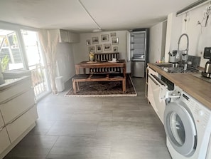 Eine kleine Küche mit Waschmaschine, einem Essbereich mit einer Bank und einem Kühlschrank.
