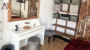 Een wit bureau met een spiegel, grijze opbergdozen en een houten plankunit.