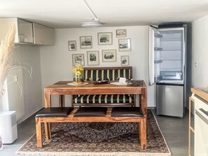 A dining area with a wooden table, benches, and a refrigerator.