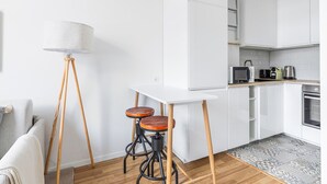 Cozinha moderna com armários brancos, micro-ondas, chaleira e cafeteira na bancada.