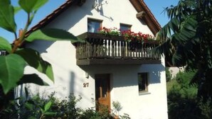 A two-story house with a balcony, surrounded by greenery. - Apartment Mund by Interhome (Dresden)