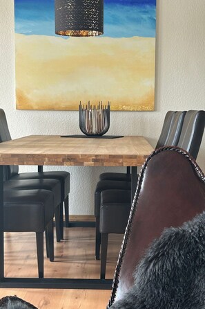 Ein Essbereich mit Holztisch, schwarzen Stühlen und einer modernen Pendelleuchte.