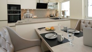 A modern kitchen with built-in appliances, a dining area with a table set for two, and a comfortable seating arrangement. - Quartier 23 by Interhome (Nordhorn)