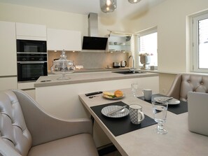 A modern kitchen with built-in appliances, a dining area with a table set for two, and a comfortable seating arrangement. - Quartier 23 by Interhome (Nordhorn)
