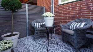 A patio area with wicker furniture, a small table, and potted plants. - Quartier 23 by Interhome (Nordhorn)