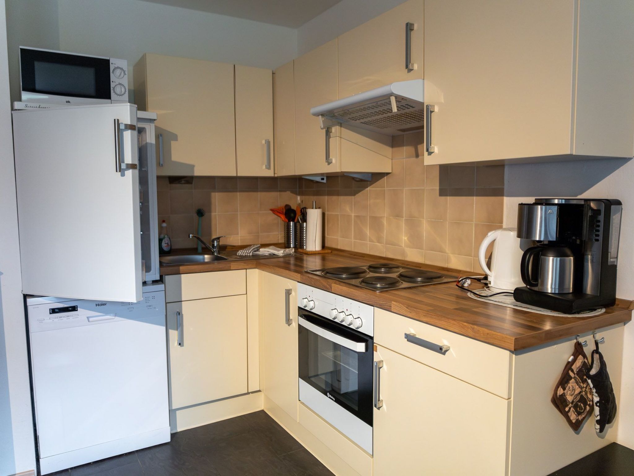 Una cocina compacta equipada con microondas, refrigerador, estufa, horno y cafetera.