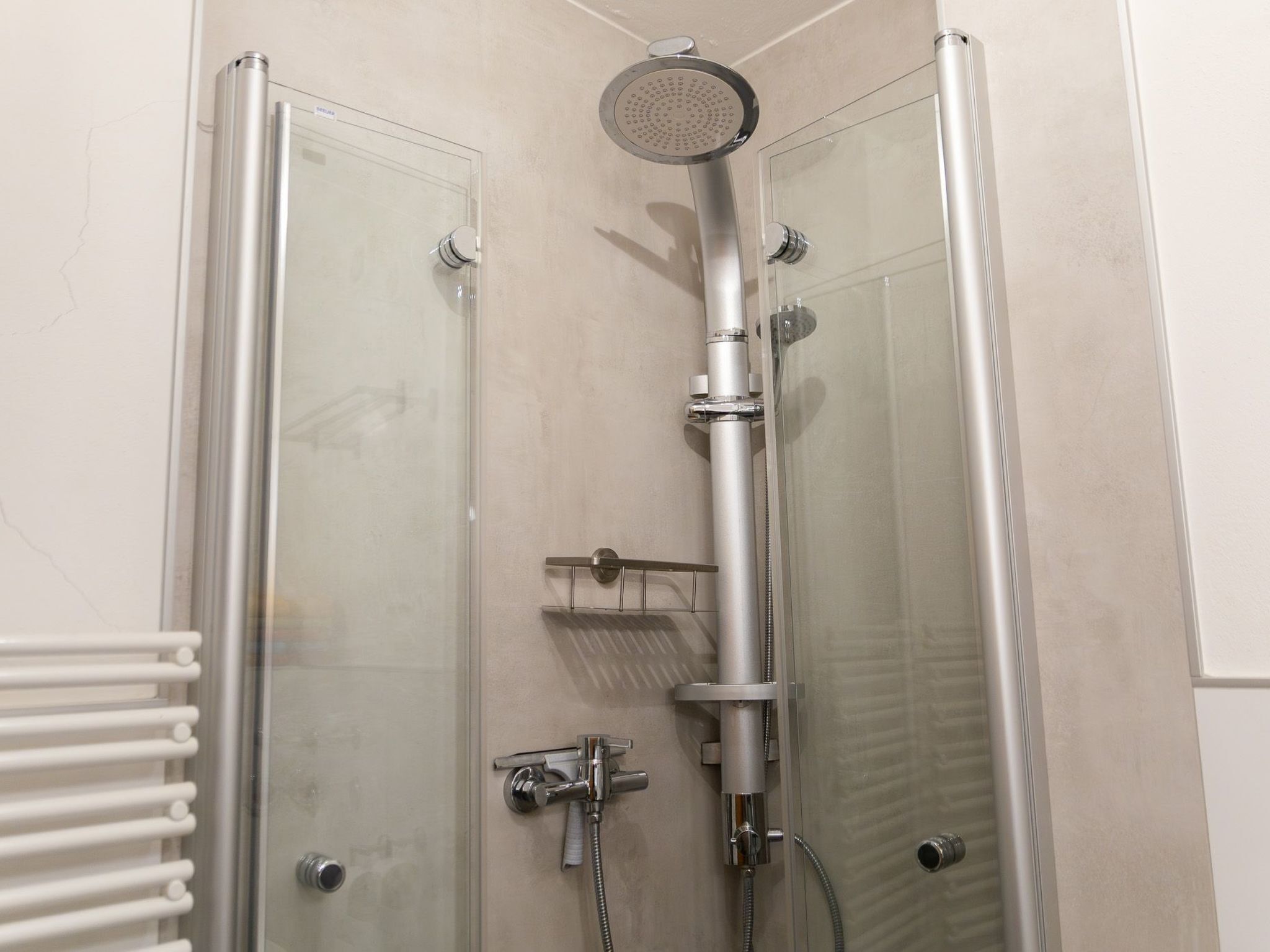A walk-in shower with a glass door, a handheld showerhead, and a handheld shower attachment.