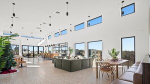 Un intérieur spacieux et moderne, doté de hauts plafonds, de grandes fenêtres et d’un agencement varié comprenant un canapé, une table à manger et des chaises.