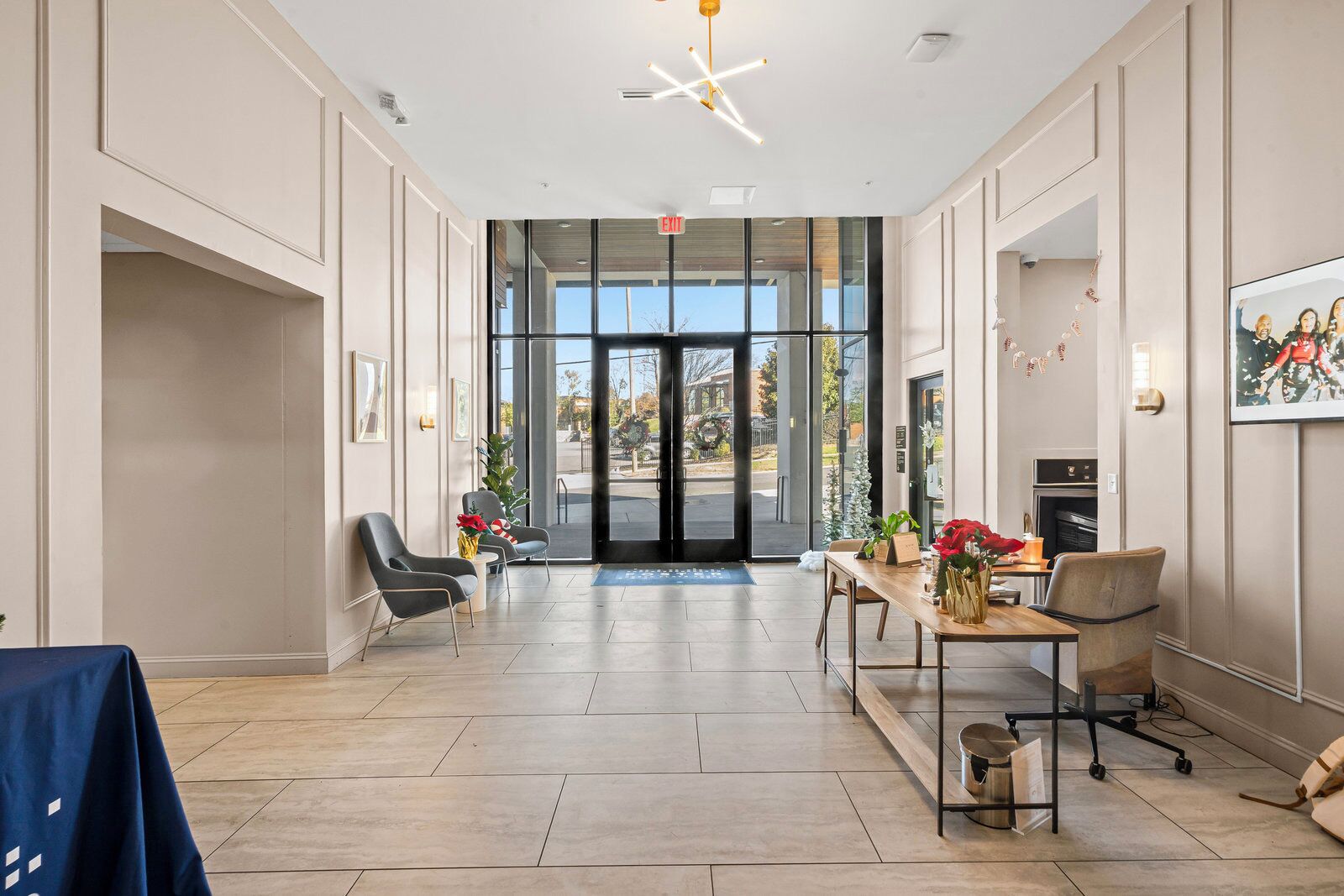 Un hall d’entrée spacieux au design moderne, comprenant un comptoir d’accueil, un espace salon et une vue dégagée grâce aux portes vitrées.