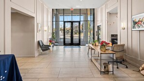 Un hall d’entrée spacieux au design moderne, comprenant un comptoir d’accueil, un espace salon et une vue dégagée grâce aux portes vitrées.