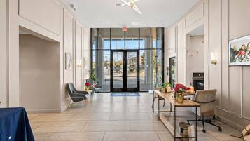 Un hall d’entrée spacieux au design moderne, comprenant un comptoir d’accueil, un espace salon et une vue dégagée grâce aux portes vitrées.
