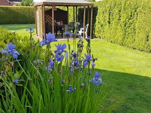 A gazebo with a table and chairs, surrounded by a well-manicured lawn and a hedge. - Ferienvilla mit Garten, Grill und Terrasse by Interhome (Dörpen)