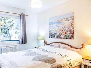 A bedroom with a bed, a window with curtains, a radiator, a painting, and a bedside table with a lamp. - Kellerwald by Interhome (Frankenau)